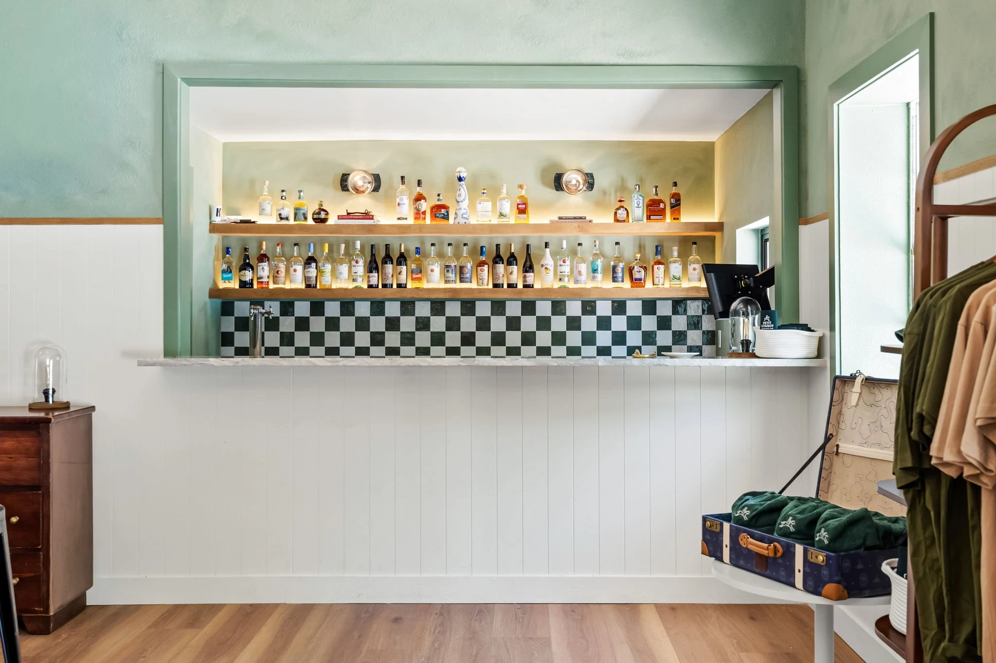 The bar, checkerboard tile & lit oak shelves at La Piscine, bar & restaurant in New Braunfels, Texas